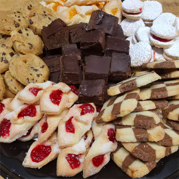 An overflowing plate of moist brownies, soft chocolate chip cookies, and flakey Kolacky and sandwich cookies with jams